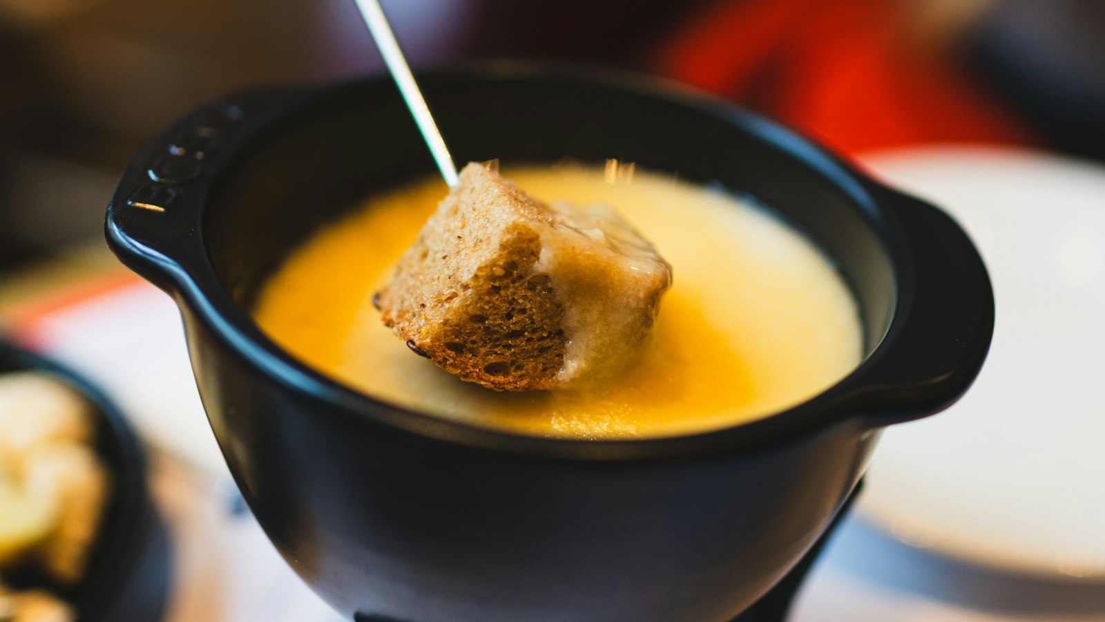 A piece of bread dipped in a pot of cheese fondue